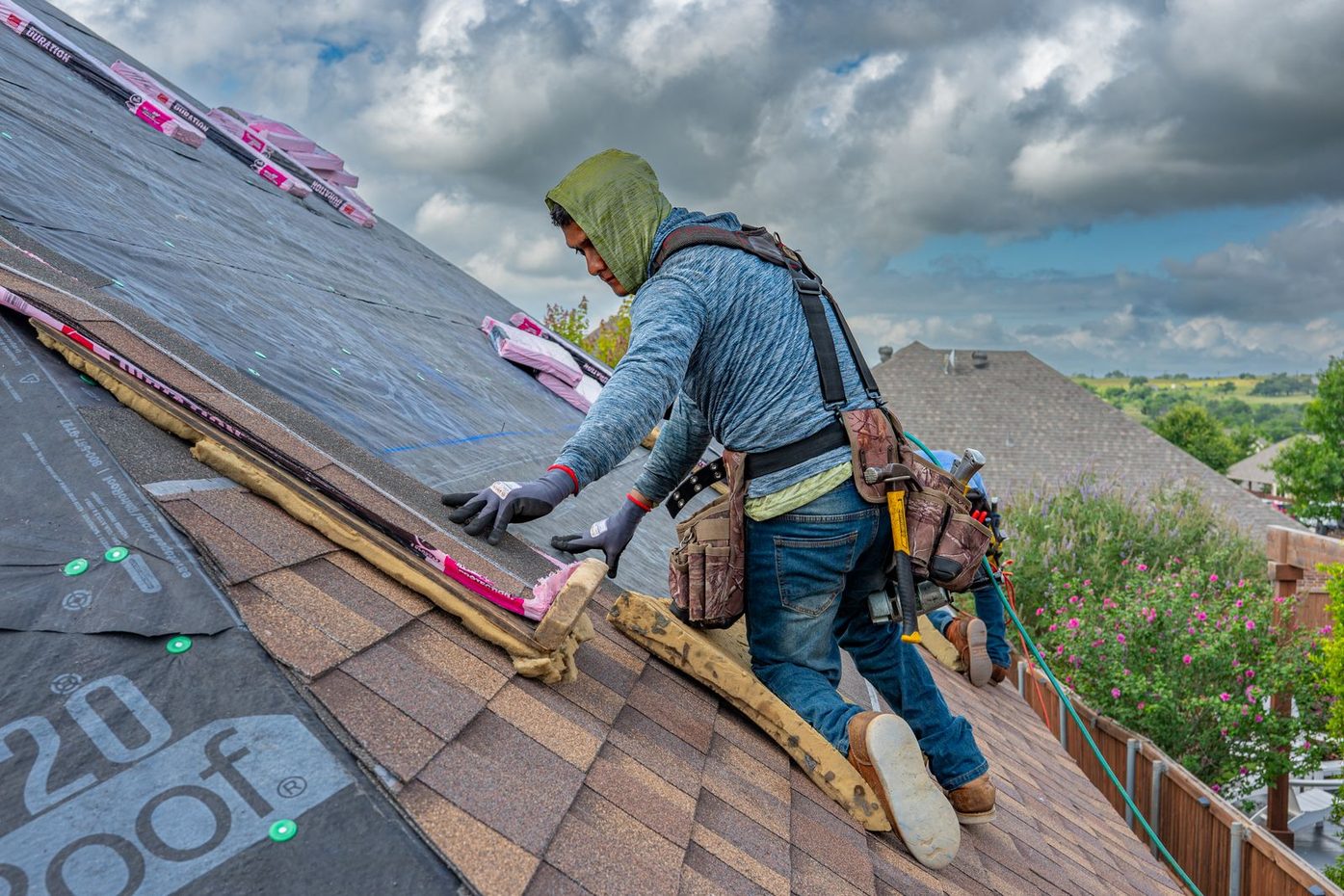 Roofer installing asphalt shingles on a pitched residential roof
